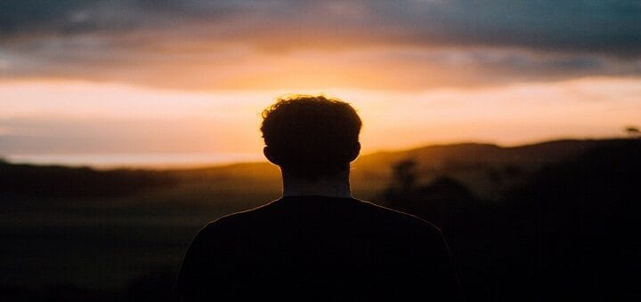 Hombre de espaldas mirando un atardecer, en una profunda reflexión sobre lo que implica avanzar sin ti después de un momento de tristeza.